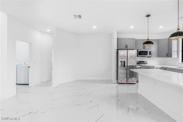 kitchen with washer / clothes dryer, appliances with stainless steel finishes, gray cabinetry, and decorative light fixtures