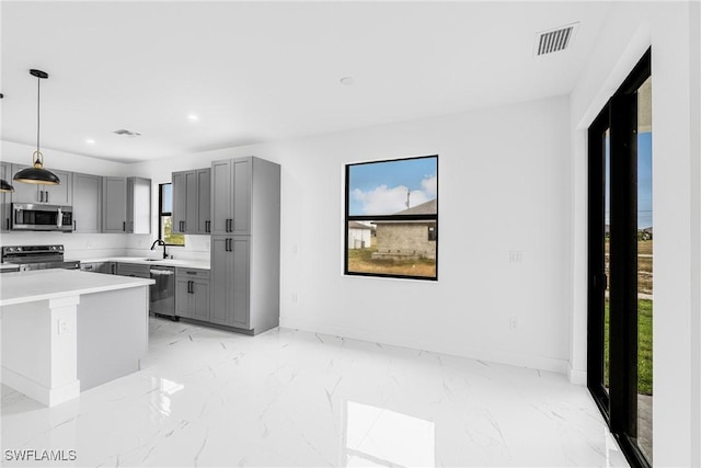 kitchen with appliances with stainless steel finishes, decorative light fixtures, sink, gray cabinetry, and a water view