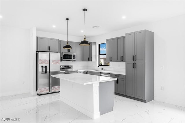 kitchen with gray cabinets, appliances with stainless steel finishes, pendant lighting, sink, and a center island