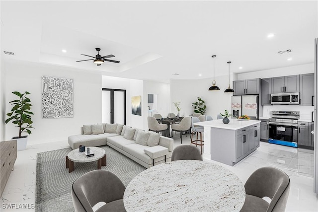 living room featuring ceiling fan and a tray ceiling