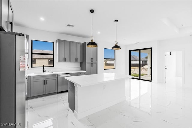 kitchen featuring sink, appliances with stainless steel finishes, gray cabinetry, hanging light fixtures, and a center island