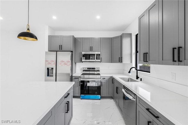 kitchen with appliances with stainless steel finishes, decorative light fixtures, sink, and gray cabinetry