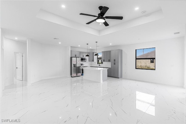 living room with a raised ceiling and ceiling fan