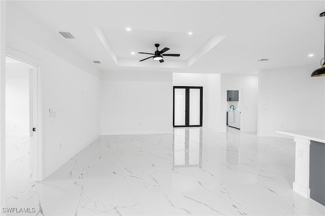 unfurnished room with a tray ceiling, french doors, and ceiling fan