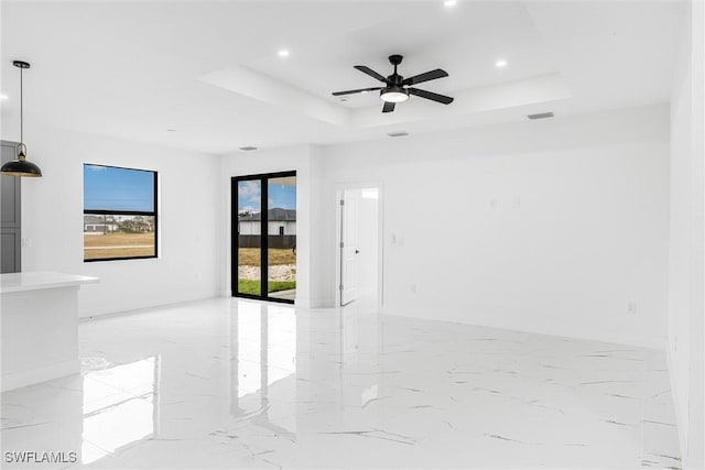 spare room with ceiling fan and a raised ceiling