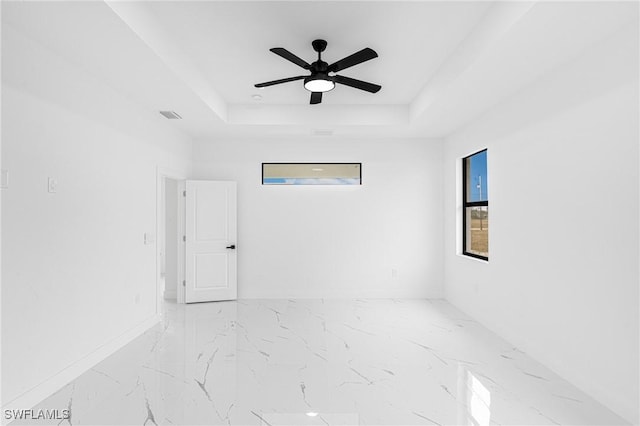 spare room featuring a raised ceiling and ceiling fan