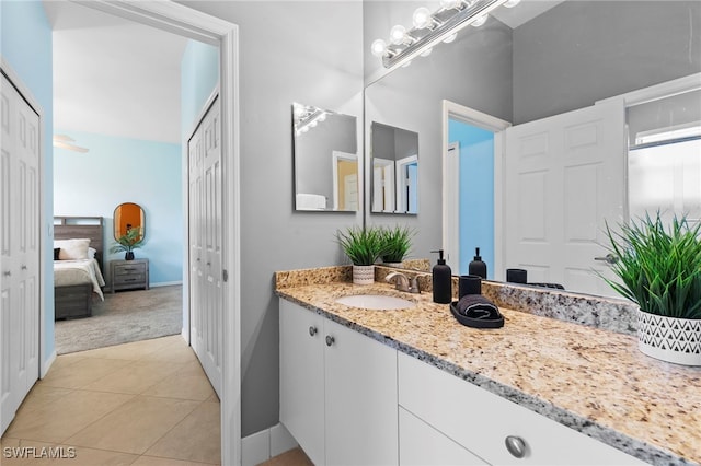 ensuite bathroom with tile patterned flooring, vanity, ensuite bath, and baseboards