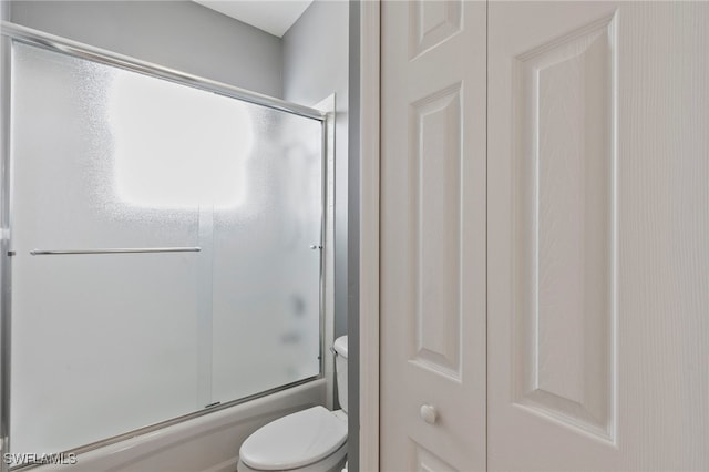 full bathroom featuring toilet and shower / bath combination with glass door