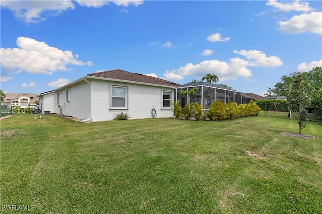 back of property with a lanai, a yard, fence, and stucco siding