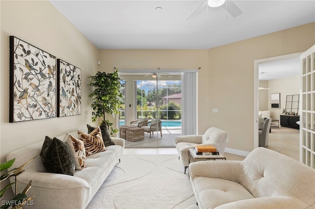 living room featuring light tile patterned flooring, baseboards, and ceiling fan