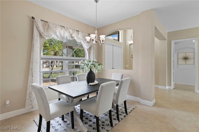 dining room with light tile patterned floors, arched walkways, baseboards, and an inviting chandelier