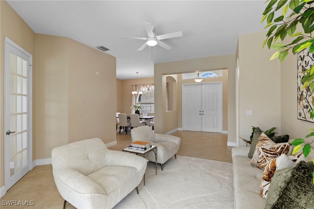 living area with visible vents, baseboards, and ceiling fan with notable chandelier