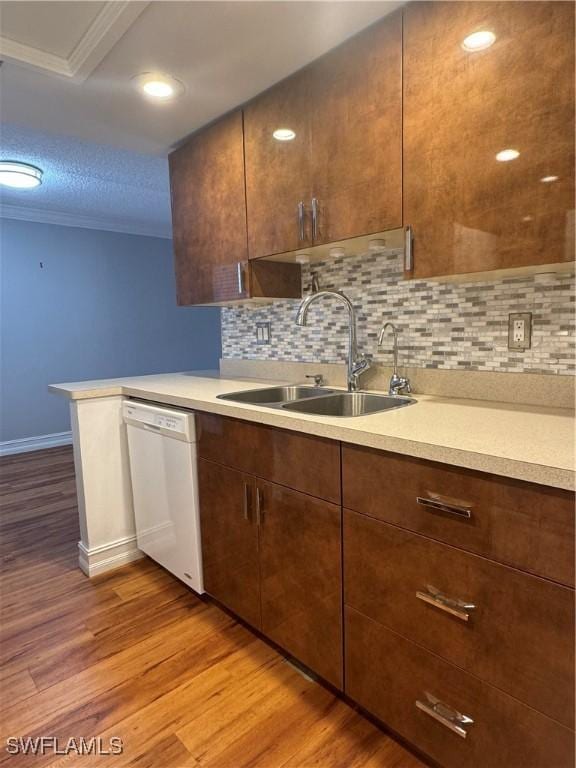 kitchen featuring tasteful backsplash, dishwasher, light countertops, light wood-style floors, and a sink