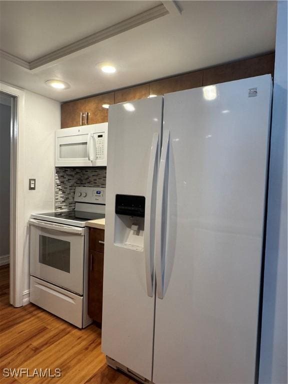 kitchen featuring recessed lighting, light countertops, backsplash, light wood-style floors, and white appliances