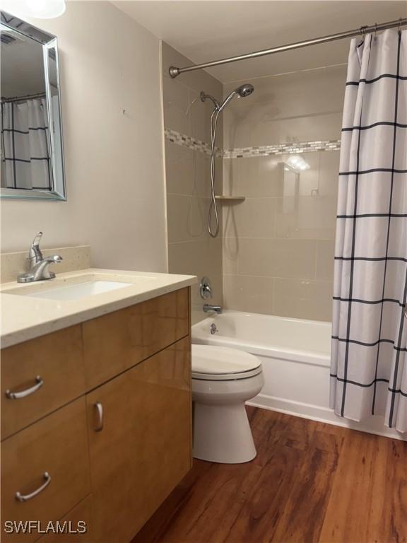 bathroom with toilet, shower / tub combo, wood finished floors, and vanity