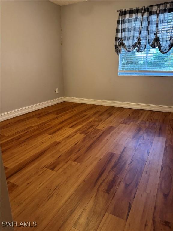 unfurnished room featuring baseboards and wood finished floors