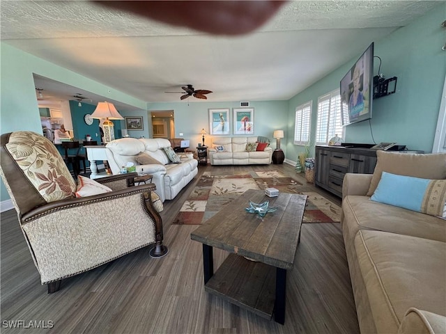 living room with ceiling fan, dark hardwood / wood-style flooring, and a textured ceiling