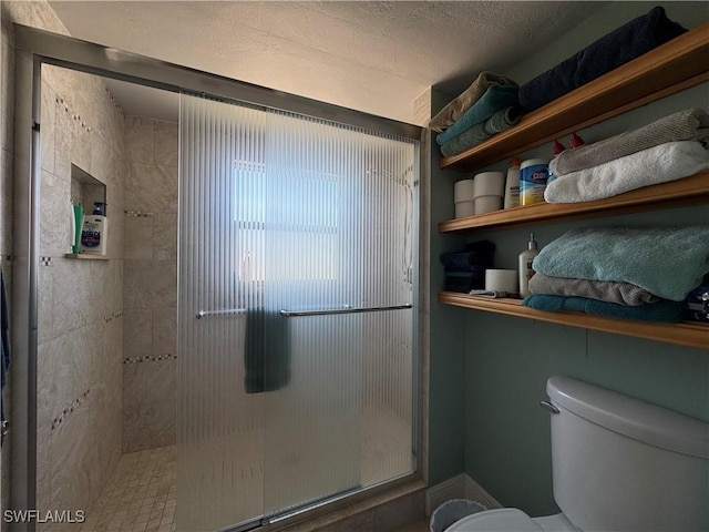 bathroom featuring an enclosed shower, a textured ceiling, and toilet