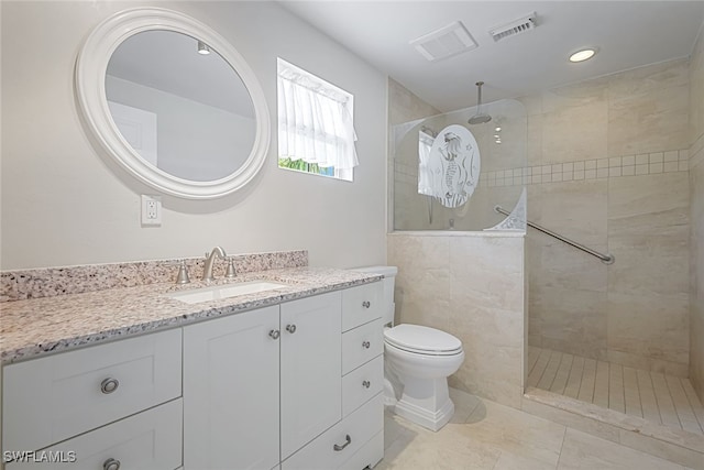 bathroom with vanity, tiled shower, tile patterned floors, and toilet