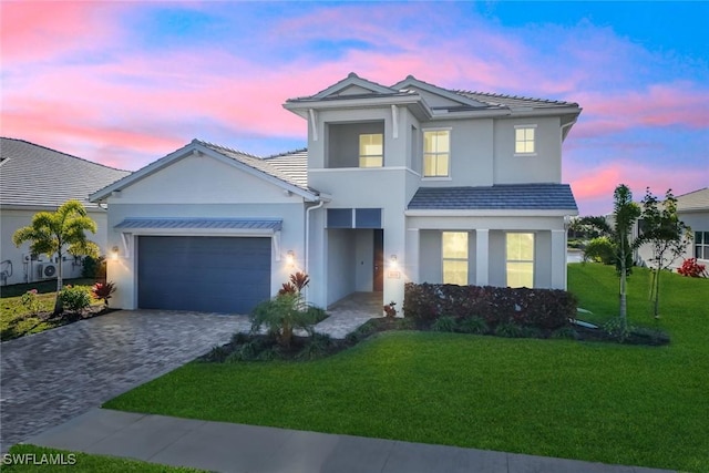 view of front of property with decorative driveway, a tile roof, stucco siding, a garage, and a front lawn