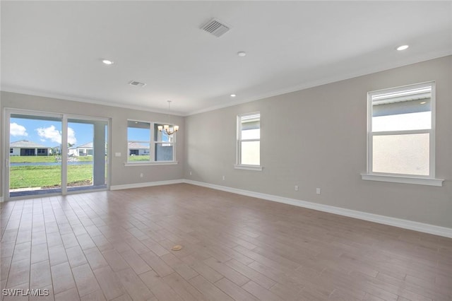 unfurnished room featuring ornamental molding, an inviting chandelier, and light hardwood / wood-style flooring