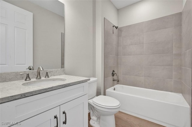 full bathroom featuring hardwood / wood-style flooring, tiled shower / bath, vanity, and toilet