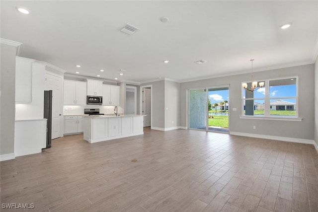 kitchen featuring a center island with sink, appliances with stainless steel finishes, a notable chandelier, light hardwood / wood-style floors, and white cabinets