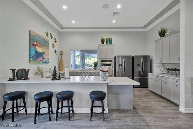 kitchen with tasteful backsplash, stainless steel refrigerator with ice dispenser, a kitchen breakfast bar, and kitchen peninsula