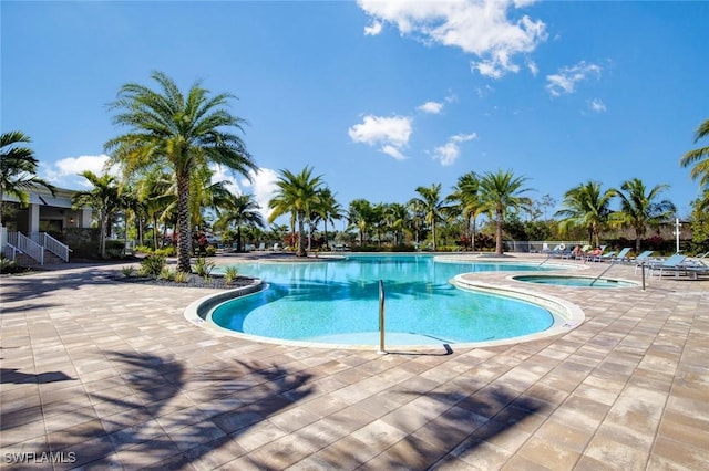 view of swimming pool featuring a hot tub and a patio