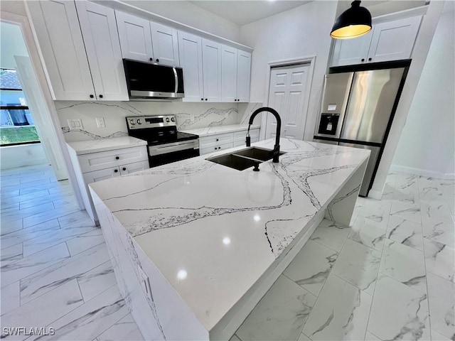 kitchen featuring appliances with stainless steel finishes, pendant lighting, sink, white cabinets, and a center island with sink