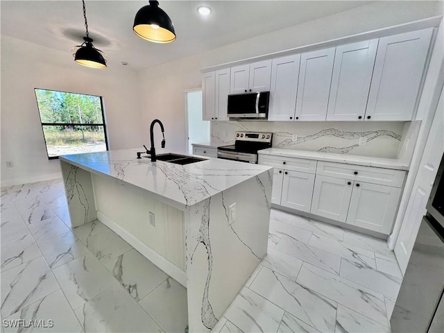 kitchen with an island with sink, appliances with stainless steel finishes, sink, and white cabinets