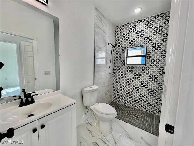 bathroom featuring vanity, toilet, and a tile shower