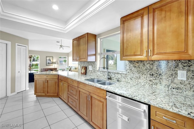 kitchen featuring sink, light stone countertops, a raised ceiling, and dishwasher