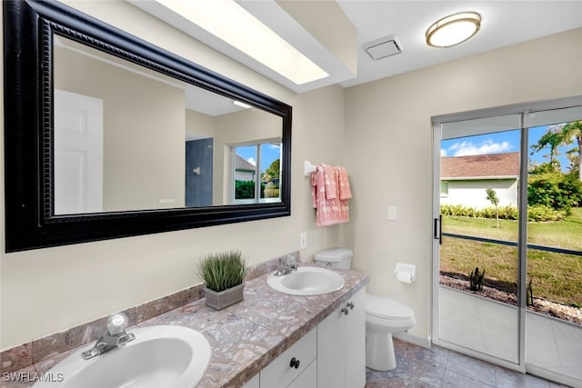 bathroom with plenty of natural light, toilet, tile patterned flooring, and vanity