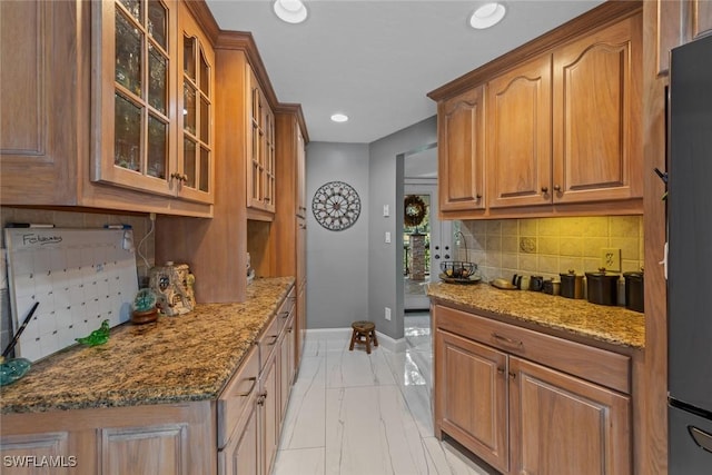 kitchen featuring stone countertops, backsplash, and refrigerator