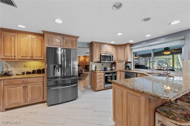 kitchen featuring sink, backsplash, light stone countertops, and appliances with stainless steel finishes