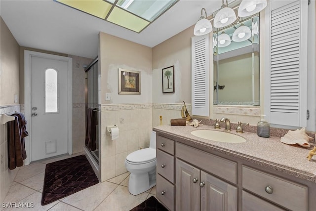 bathroom featuring vanity, tile patterned flooring, a shower with door, and tile walls