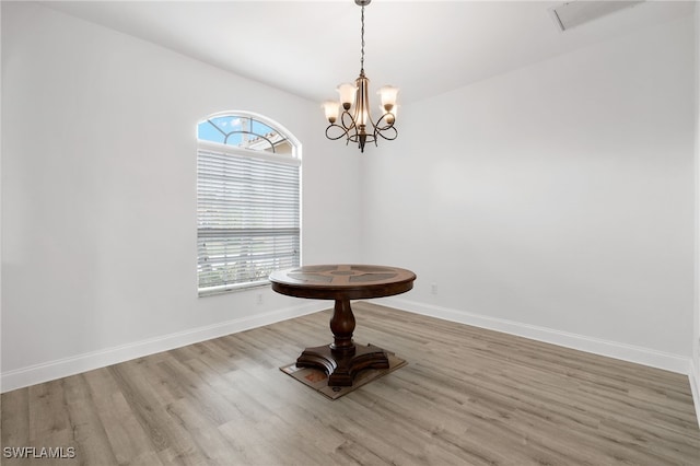 unfurnished dining area with a healthy amount of sunlight, an inviting chandelier, and light hardwood / wood-style flooring