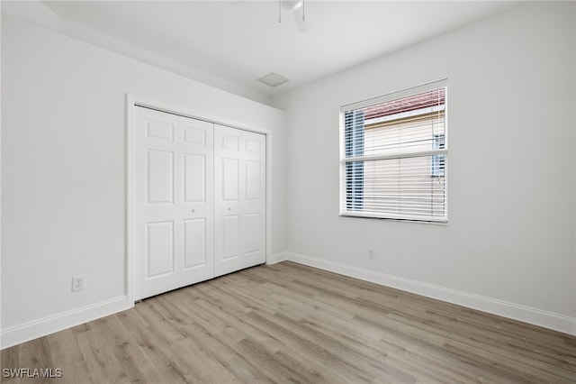 unfurnished bedroom with ceiling fan, a closet, and light wood-type flooring