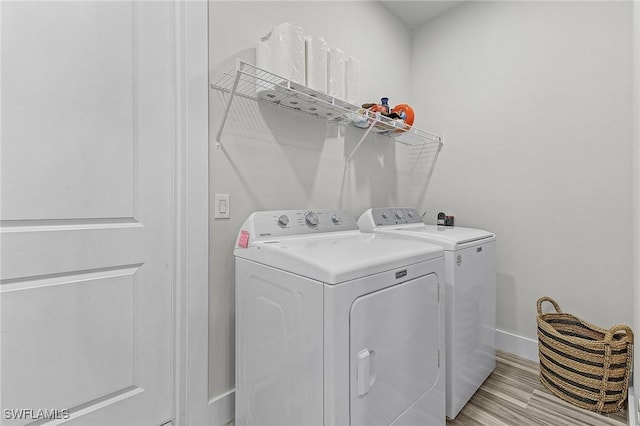 laundry area with washer and clothes dryer and light hardwood / wood-style floors