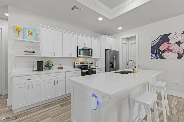 kitchen with appliances with stainless steel finishes, sink, a center island with sink, and white cabinets