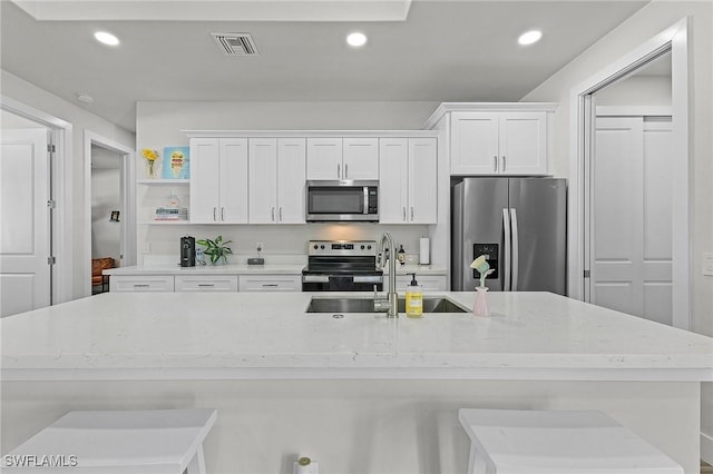 kitchen featuring white cabinetry, appliances with stainless steel finishes, sink, and a breakfast bar area