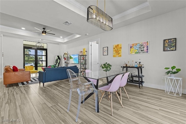 dining room with crown molding, ceiling fan, a tray ceiling, and light hardwood / wood-style flooring