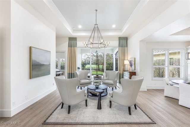 living room featuring a notable chandelier, light hardwood / wood-style flooring, a raised ceiling, and a healthy amount of sunlight