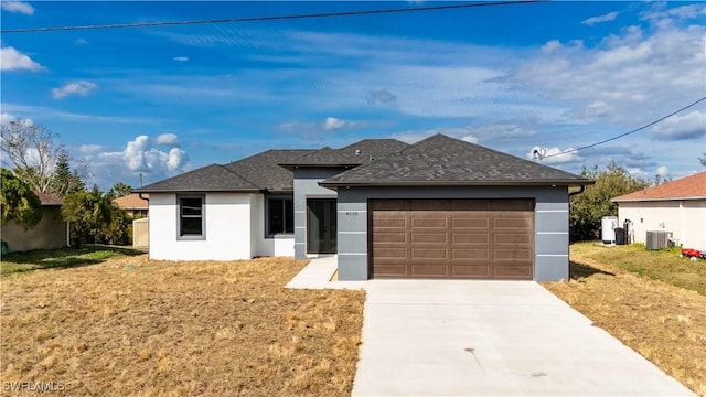 view of front of home with cooling unit, a garage, and a front yard