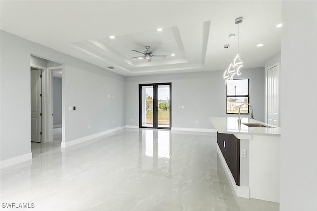 interior space with sink, a tray ceiling, and ceiling fan