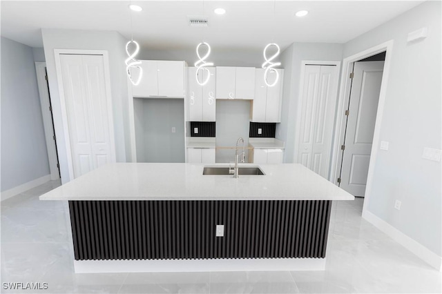 kitchen with white cabinetry, sink, a center island with sink, and pendant lighting