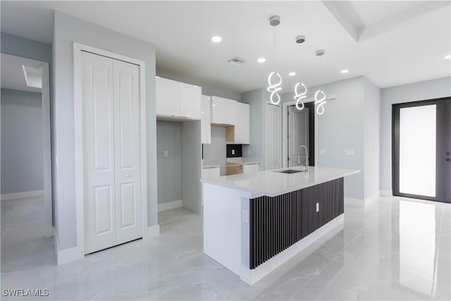 kitchen with white cabinetry, sink, pendant lighting, and a center island with sink