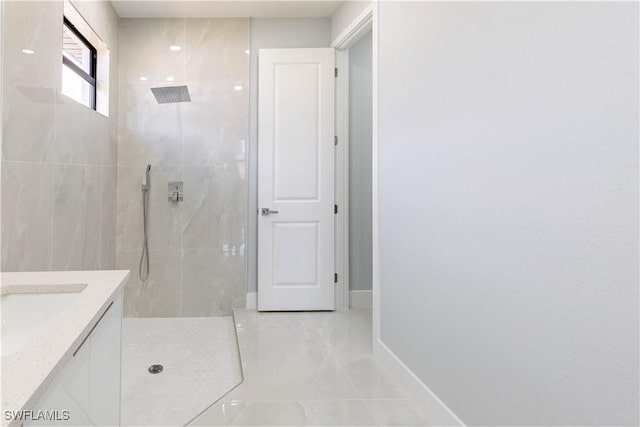 bathroom with tiled shower and vanity