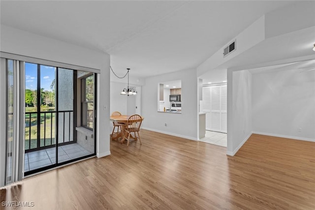 unfurnished living room featuring light wood-type flooring and an inviting chandelier